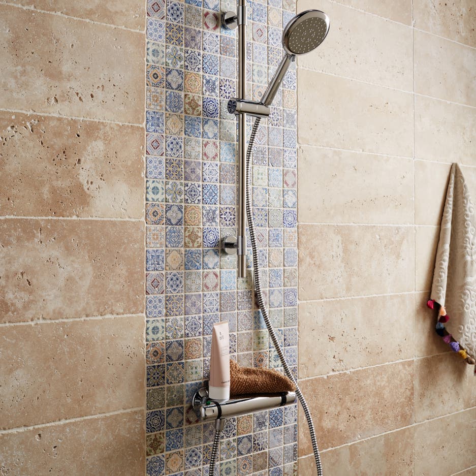 Des petits carreaux en pierre beige et bleue dans la douche Leroy Merlin